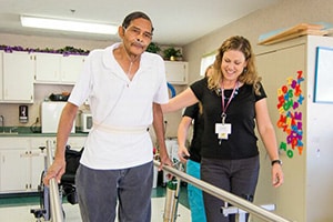 A rehab therapist and a resident walking in the rehab gym of the Richwood Nursing