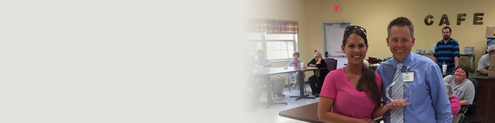 A caregiver receiving an award standing in the hallway with the administrator at Richwood Nursing